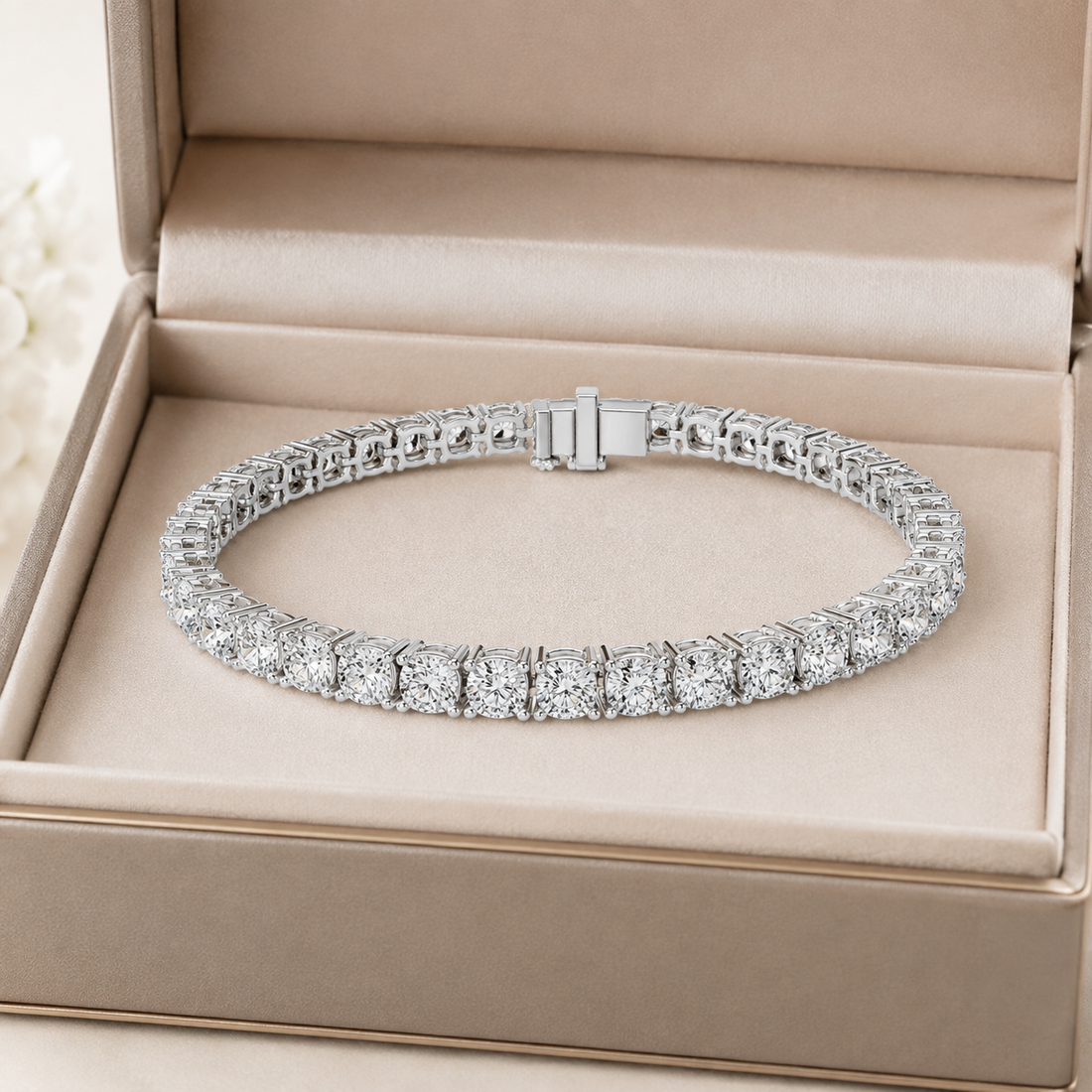 A silver tennis bracelet with round-cut clear stones, displayed inside an open beige jewelry box.