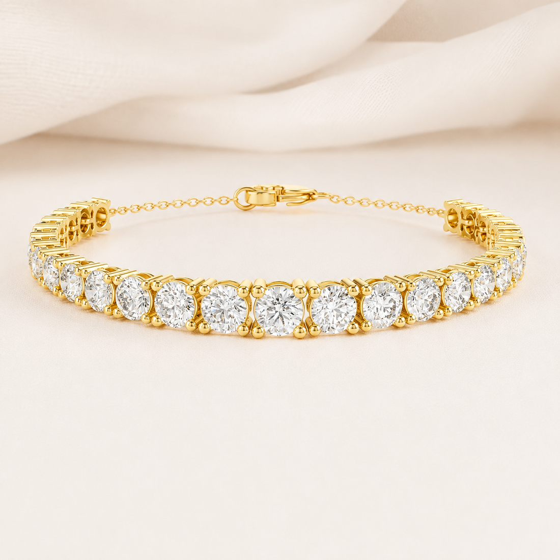 A yellow gold tennis bracelet with round-cut clear gemstones, displayed on a soft beige fabric background.