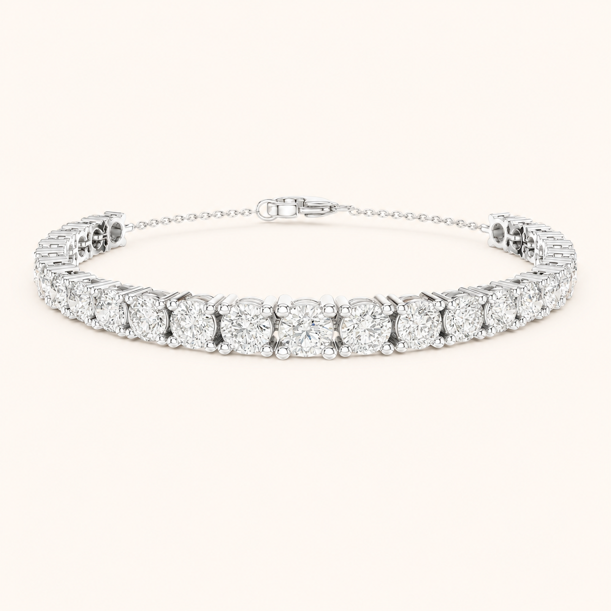 A diamond tennis bracelet with a silver-toned metal setting, featuring a row of round brilliant-cut diamonds and a delicate extender chain with a lobster clasp, shown on a light cream background.
