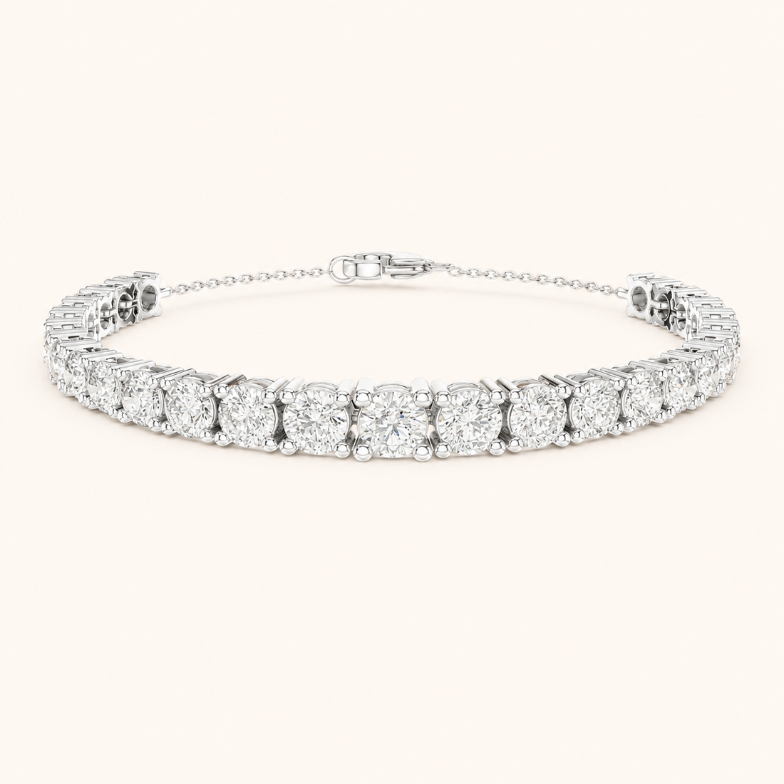 A diamond tennis bracelet with a silver-toned metal setting, featuring a row of round brilliant-cut diamonds and a delicate extender chain with a lobster clasp, shown on a light cream background.