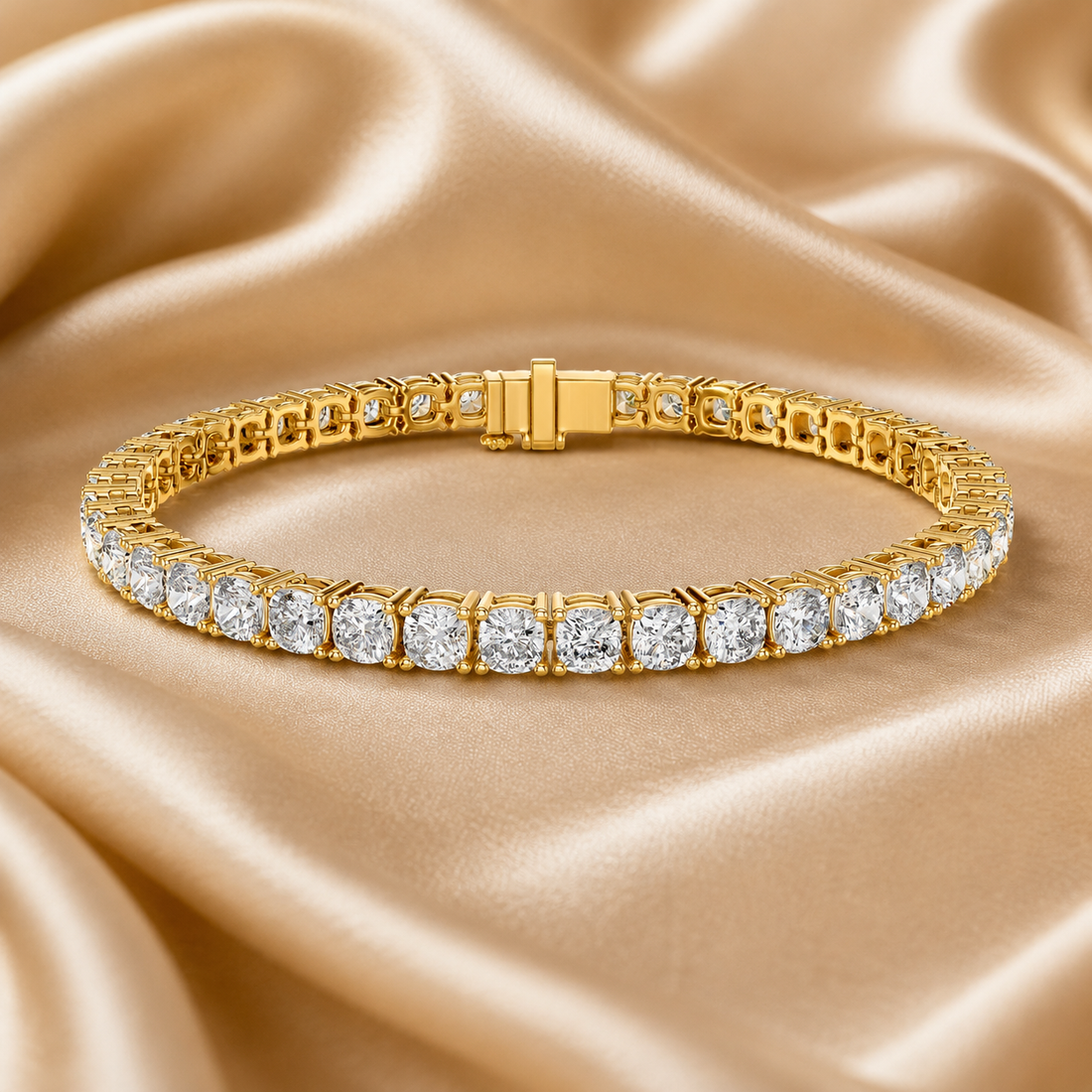 A gold tennis bracelet with round-cut clear stones, displayed on a draped champagne satin fabric background.