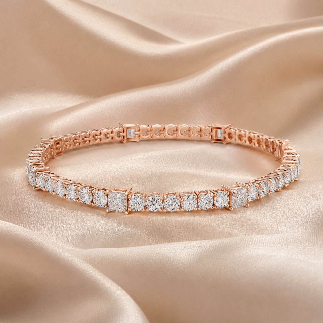 A rose gold tennis bracelet with brilliant and round-cut clear stones, displayed on a draped champagne satin fabric background.