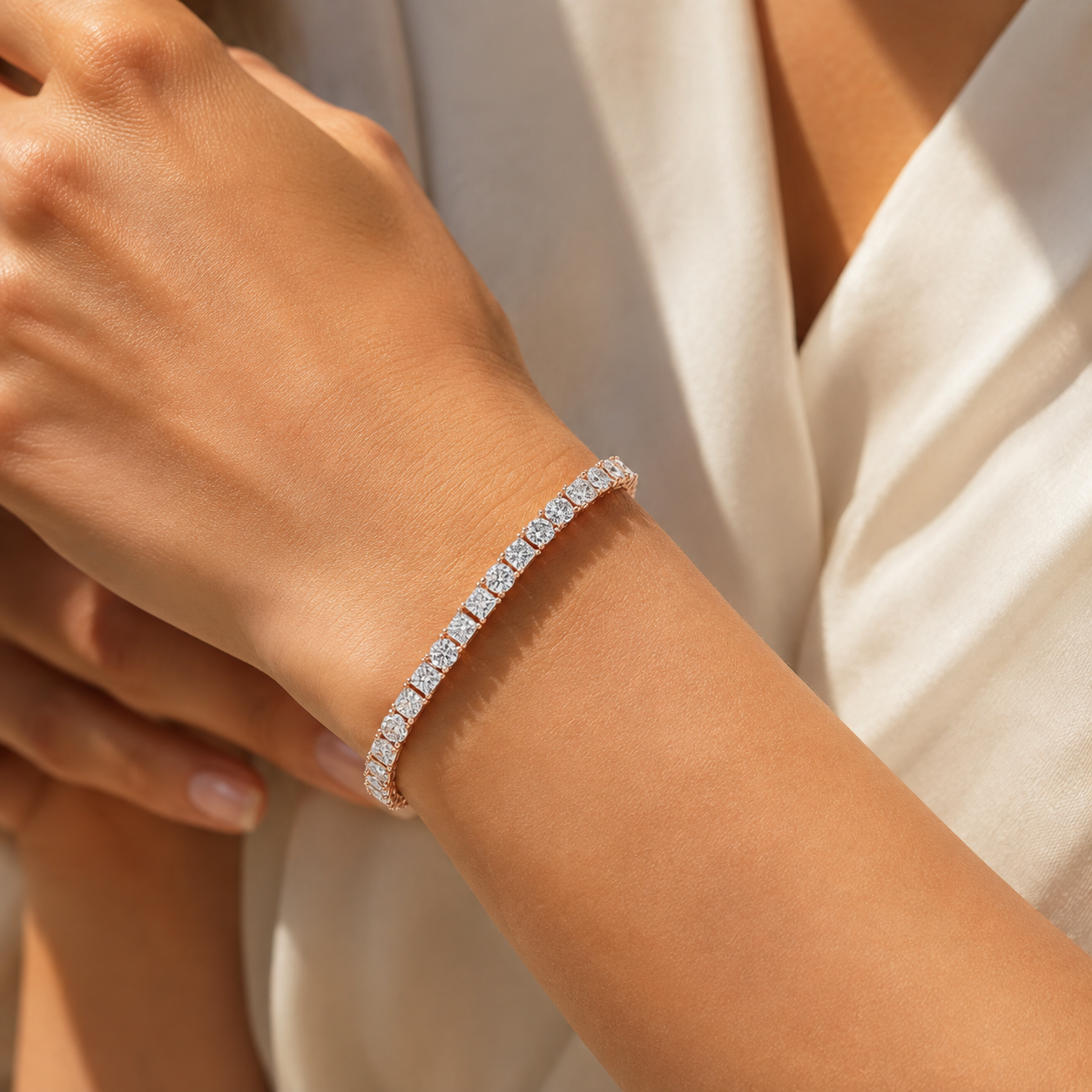 A close-up of a diamond tennis bracelet worn on a woman's wrist, styled with a white satin dress.