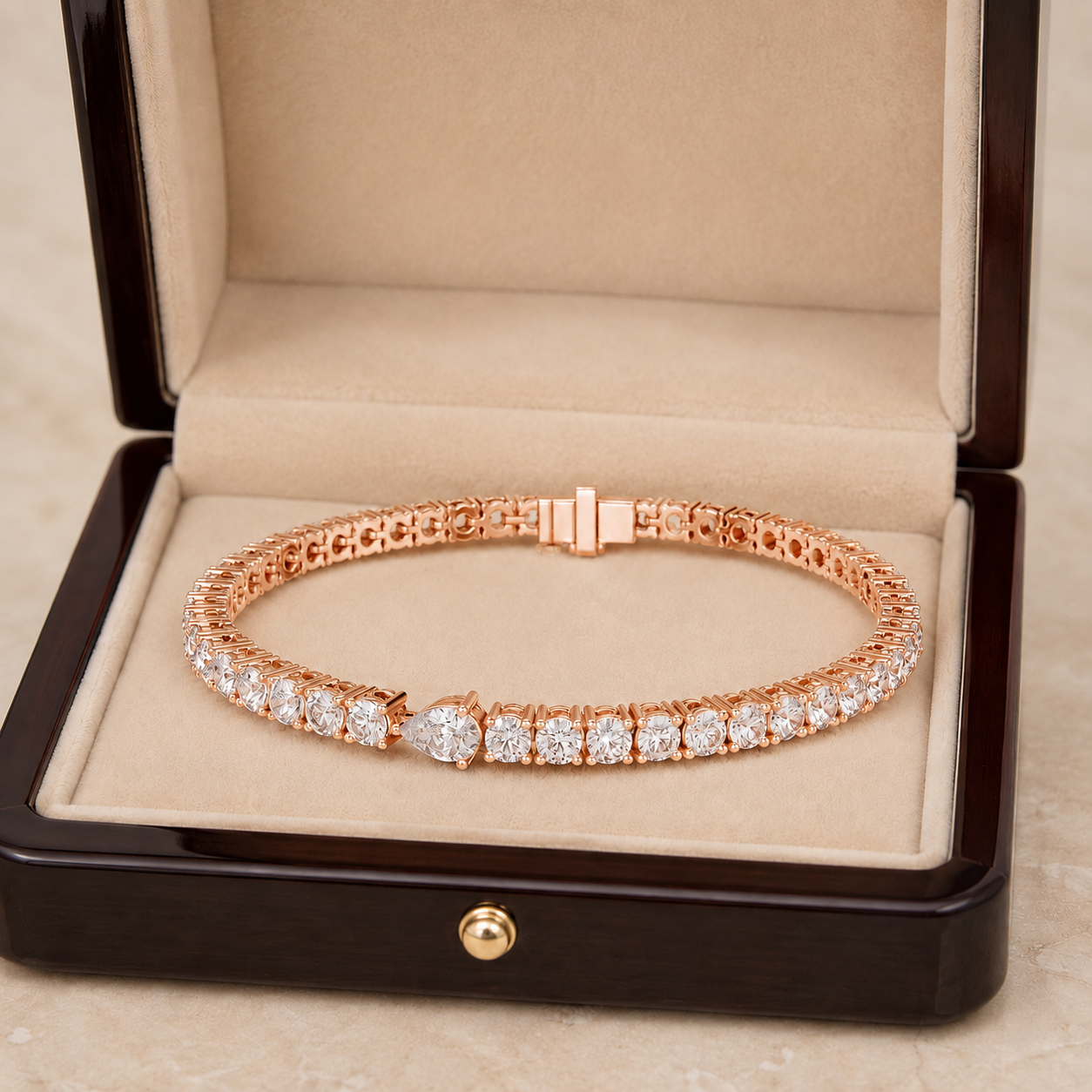 A rose gold tennis bracelet with clear gemstones, displayed inside an open dark wood jewelry box with a beige velvet lining.