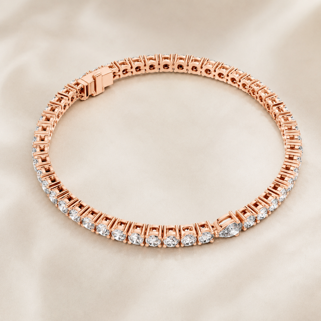 A rose gold tennis bracelet with a row of clear diamonds along the front, displayed on a soft beige satin fabric background.