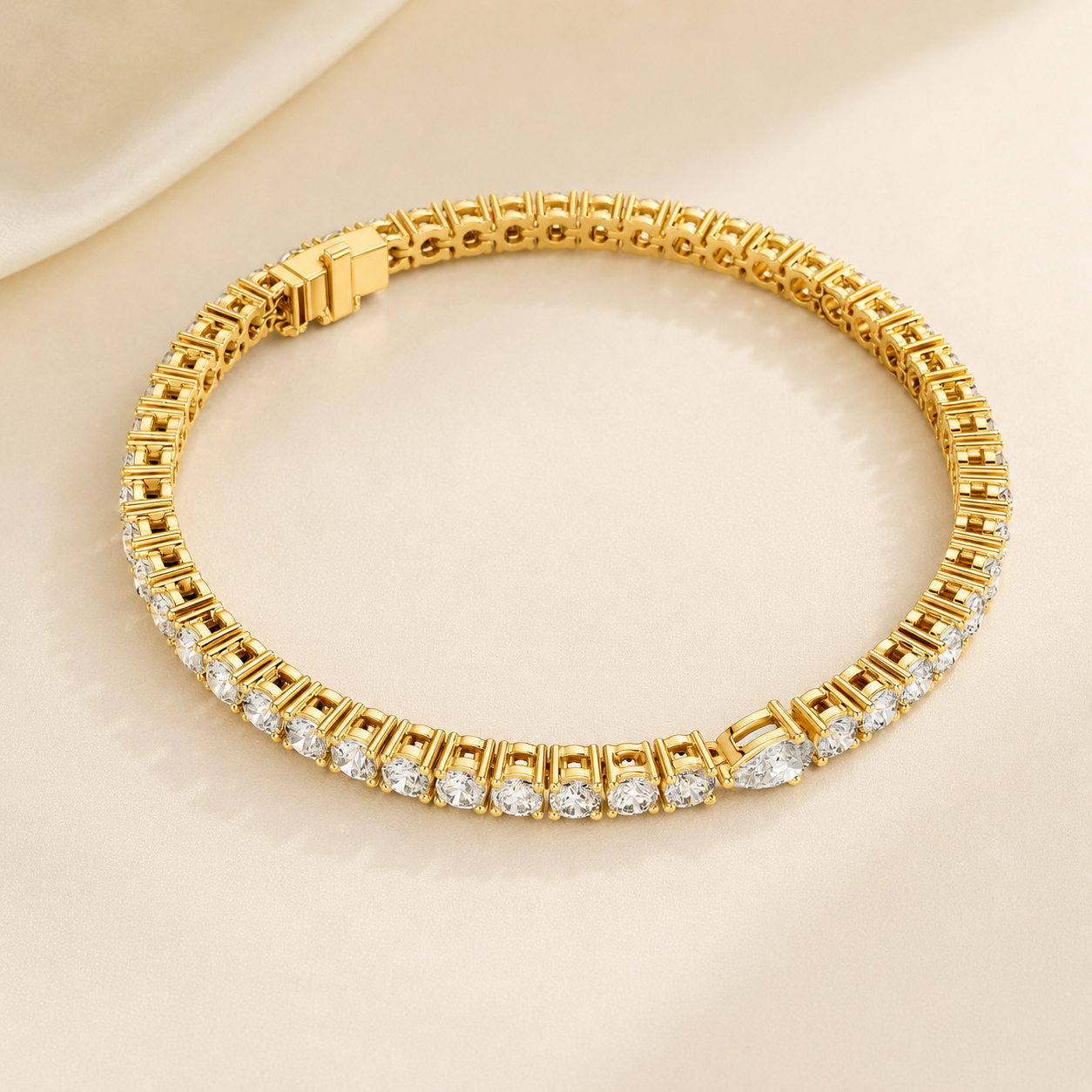 A gold tennis bracelet with a row of clear round-cut gemstones, displayed on a soft beige satin background.
