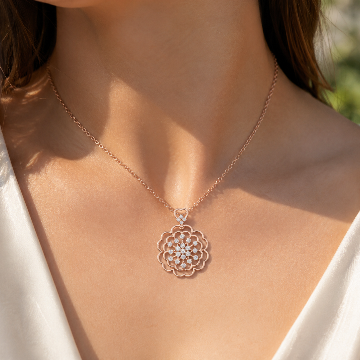 A close-up of a woman wearing a delicate rose gold necklace with a floral pendant adorned with small clear crystals.