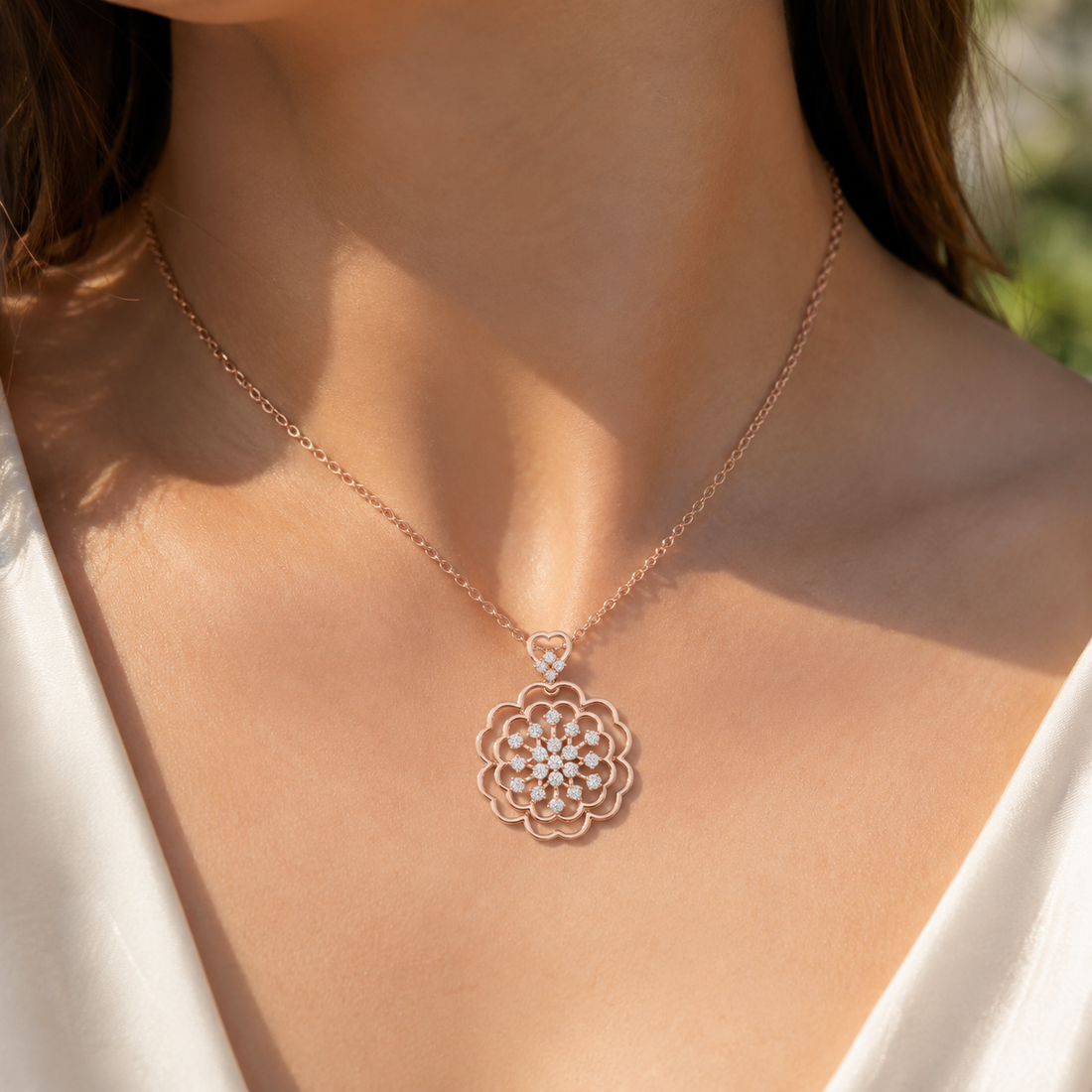 A close-up of a woman wearing a delicate rose gold necklace with a floral pendant adorned with small clear crystals.