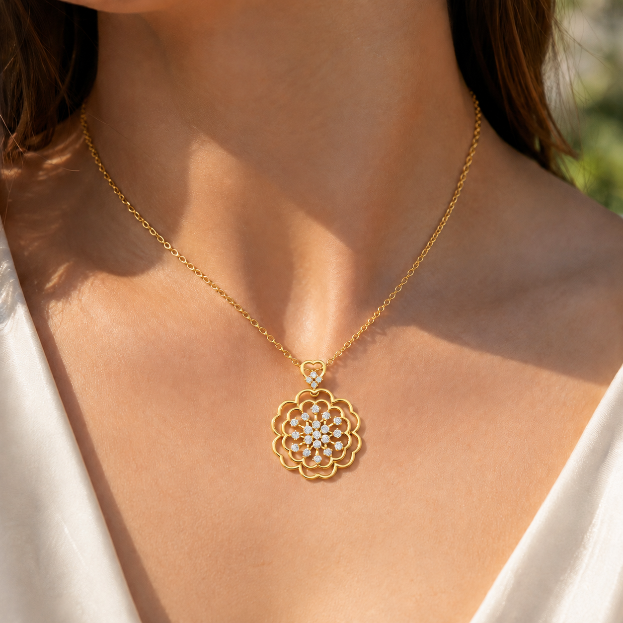 A close-up of a woman wearing a delicate gold chain necklace with a gold flower-shaped pendant featuring small clear stones, set against her neck and white top.
