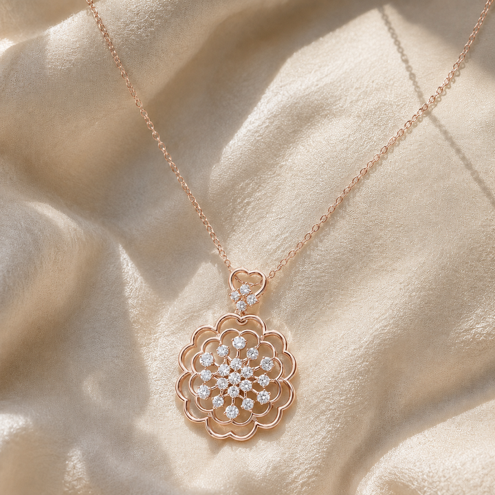Rose gold floral pendant necklace with clear gemstones, displayed on draped cream-colored satin fabric.