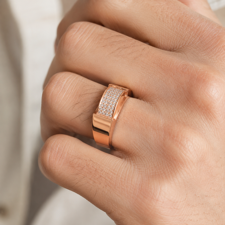 A close-up of a hand wearing a rose gold ring with a pavé-set clear stone band.
