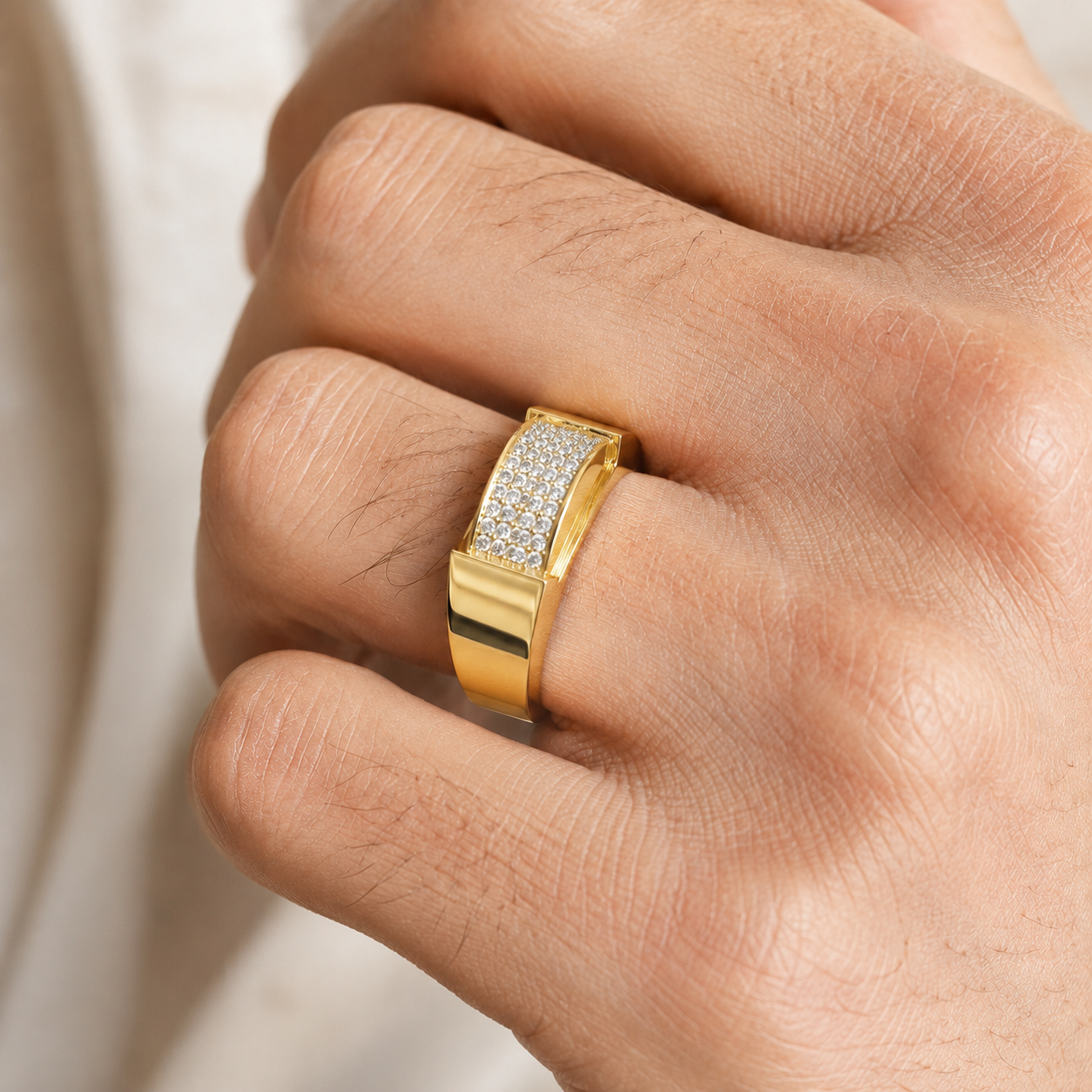 A close-up of a hand wearing a gold ring with a pavé-set clear stone band on the ring finger.