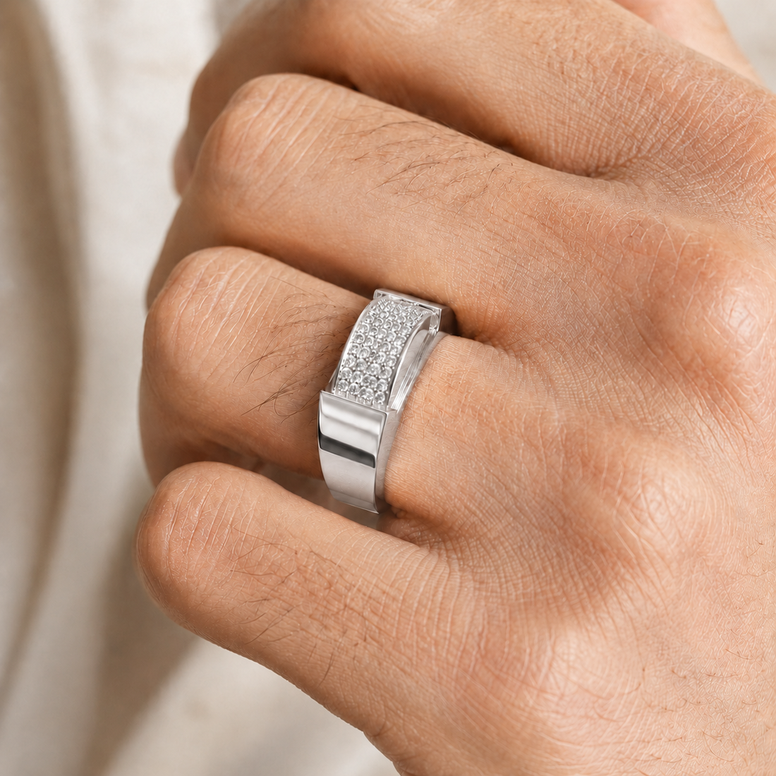 A silver-toned men's ring with a pavé-set clear stone top, shown worn on a man's ring finger.