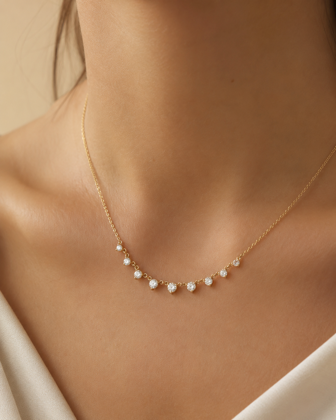 A delicate gold necklace with small white pearl-like beads and clear crystal accents, worn on a model's neck.