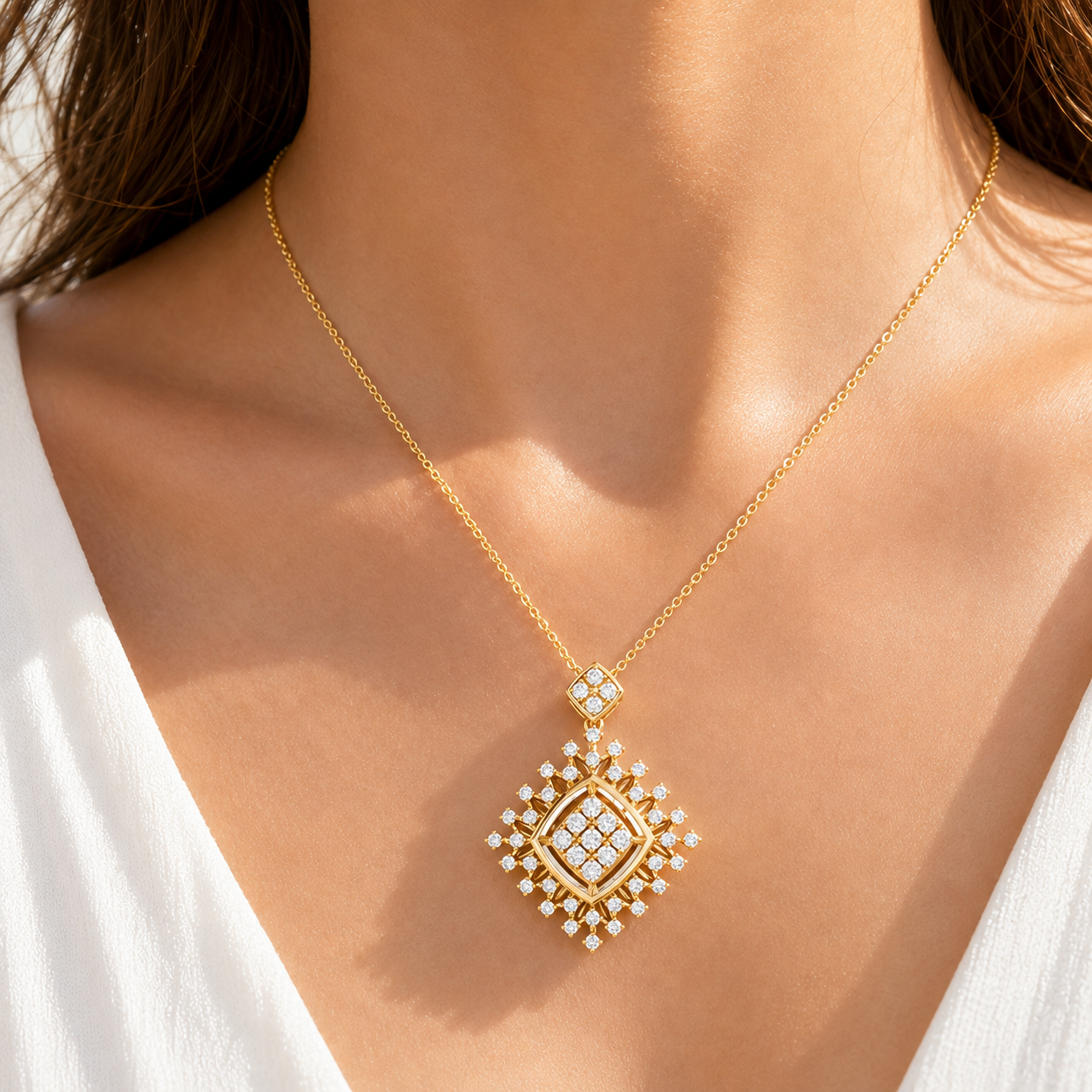 A close-up of a model wearing a gold chain necklace with a diamond-encrusted pendant. The pendant features a geometric, diamond-shaped design with a gold center and surrounding clear stones.