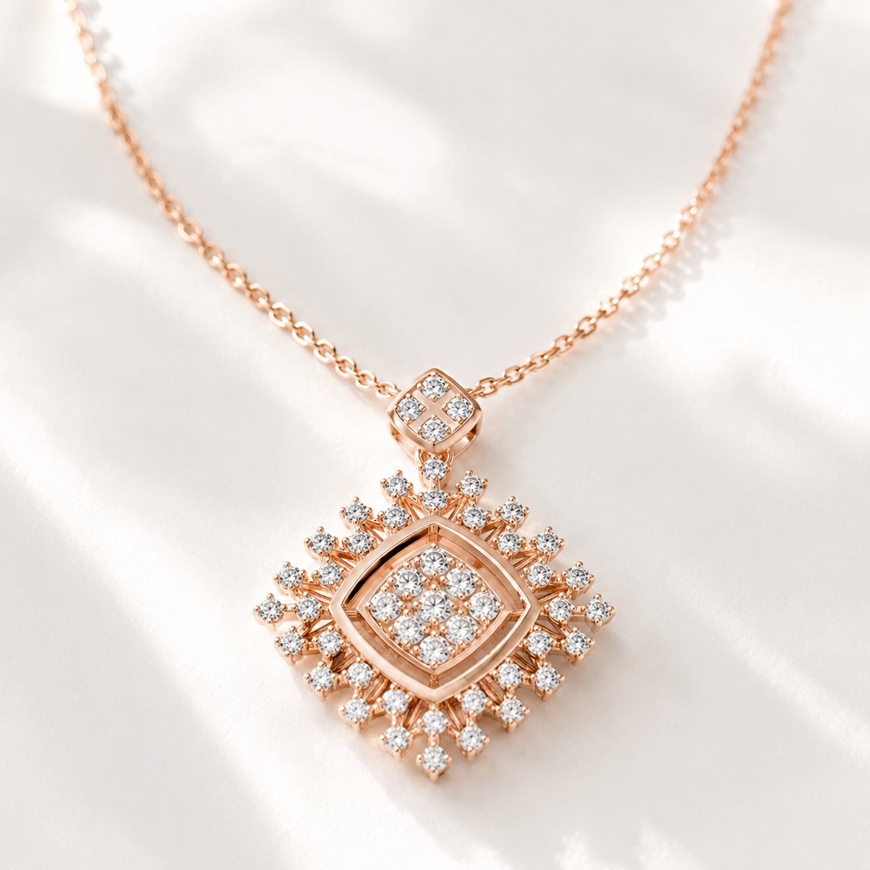 A rose gold diamond pendant necklace with a geometric sunburst design, displayed on a soft white surface with elegant shadows.