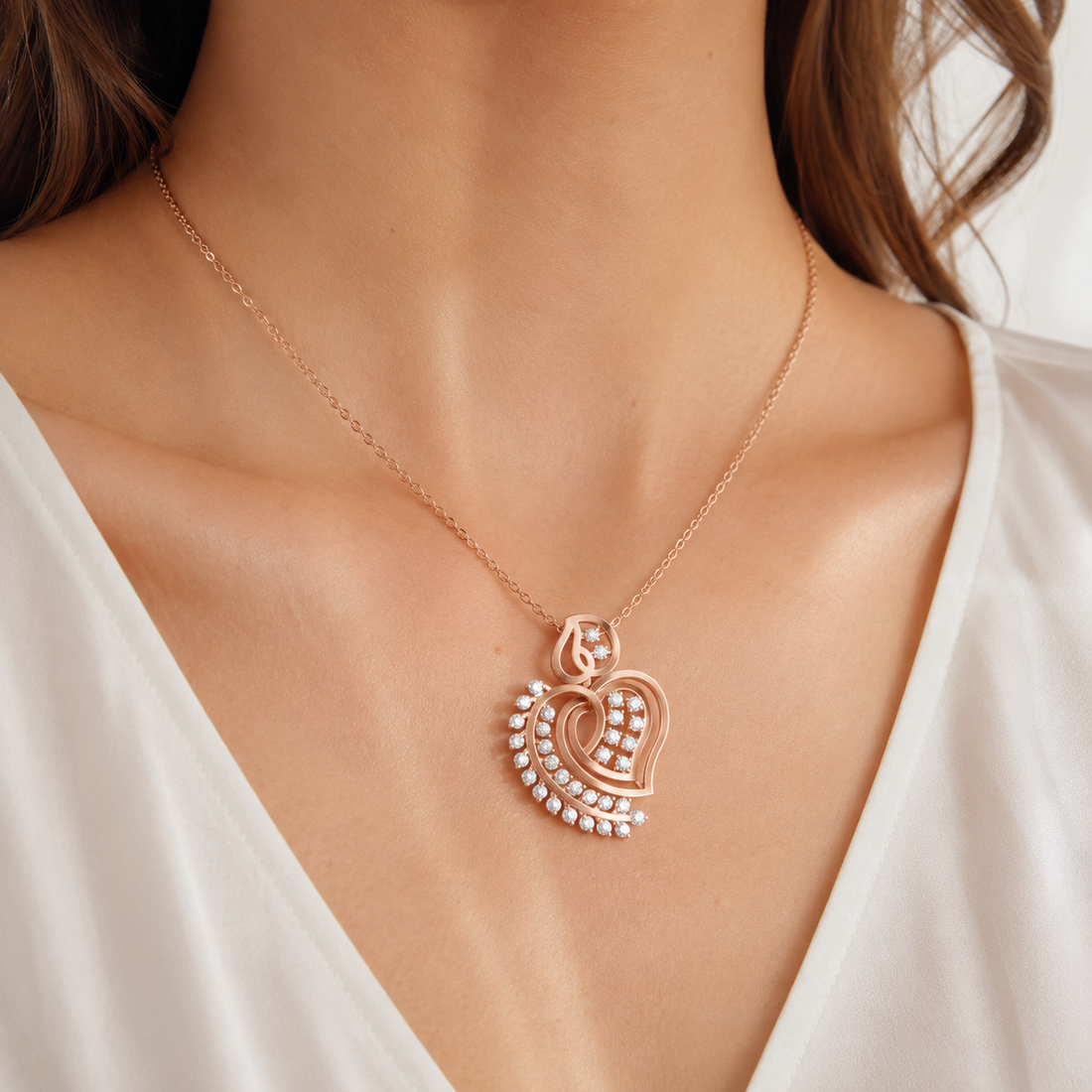 A close-up of a model wearing a delicate rose gold necklace with a heart-shaped pendant adorned with small clear stones, paired with a white V-neck top.