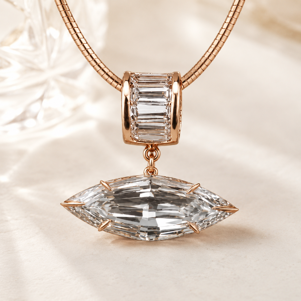 Rose gold necklace with a large marquise-cut clear crystal pendant and a smaller baguette-cut clear crystal charm, displayed on a soft cream fabric background.