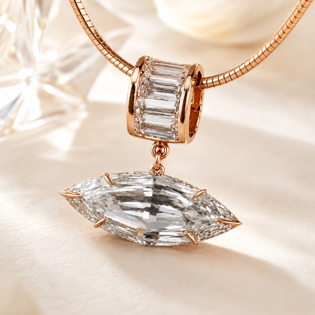 Rose gold jewelry charm featuring a marquise-cut clear baguette gemstone dangling below a rectangular baguette bezel setting, on a matching rose gold snake chain against a warm cream background.