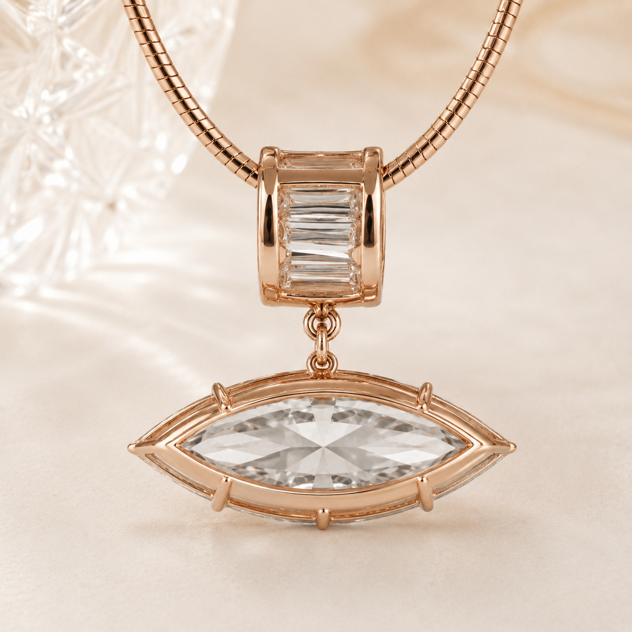 Rose gold jewelry featuring a snake chain necklace with a charm and drop pendant. The charm has a baguette-cut clear crystal, while the drop pendant is an eye-shaped marquise-cut clear crystal in a rose gold bezel setting.