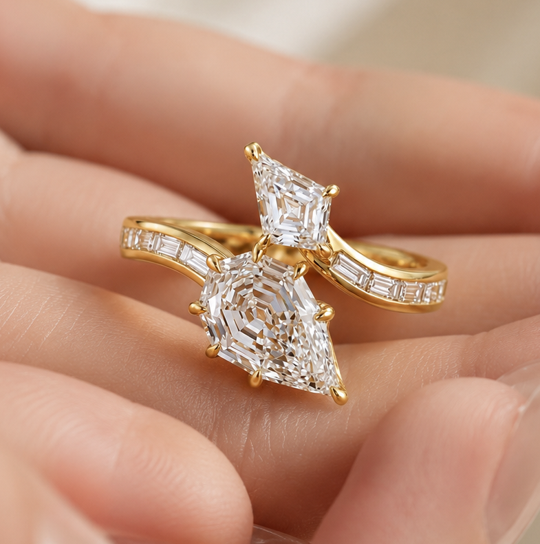 A gold ring with a large pear-cut diamond and smaller marquise-cut diamond accents, shown resting on a person's fingers against a soft cream background.