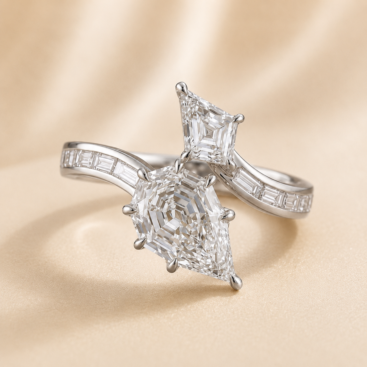 A silver engagement ring with a large pear-cut center stone and a smaller emerald-cut stone on the opposite side, set on a champagne-colored satin background.