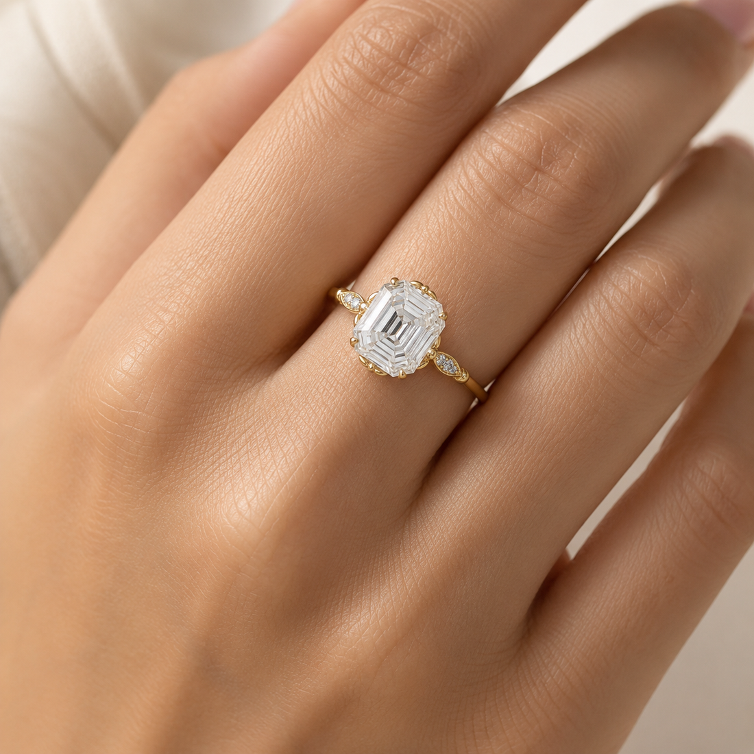 A close-up of a hand wearing a yellow gold ring with a large emerald-cut clear center stone and small side stones.