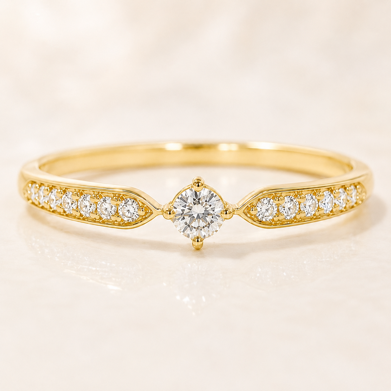 A yellow gold ring featuring a central round brilliant-cut diamond surrounded by smaller diamonds on both sides of the band, set against a soft, light beige background.