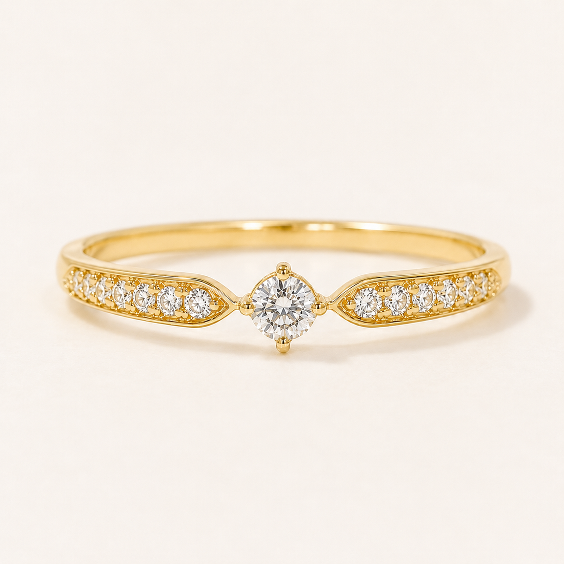 A yellow gold diamond ring with a marquise-cut center stone and pavé-set diamonds along the band, shown on a clean off-white background.