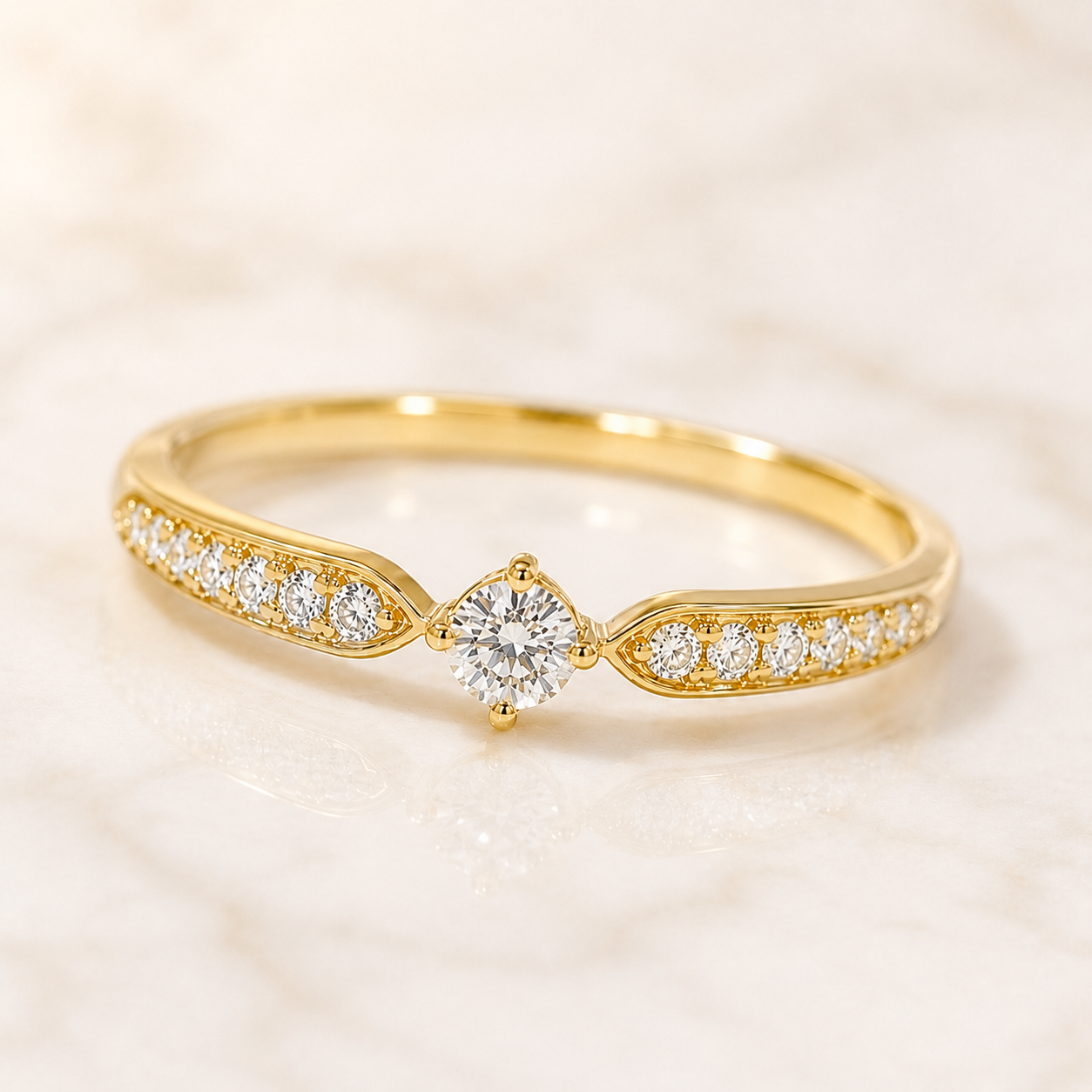 A yellow gold ring with a central round diamond and smaller diamonds set along the band, photographed on a light marble surface.