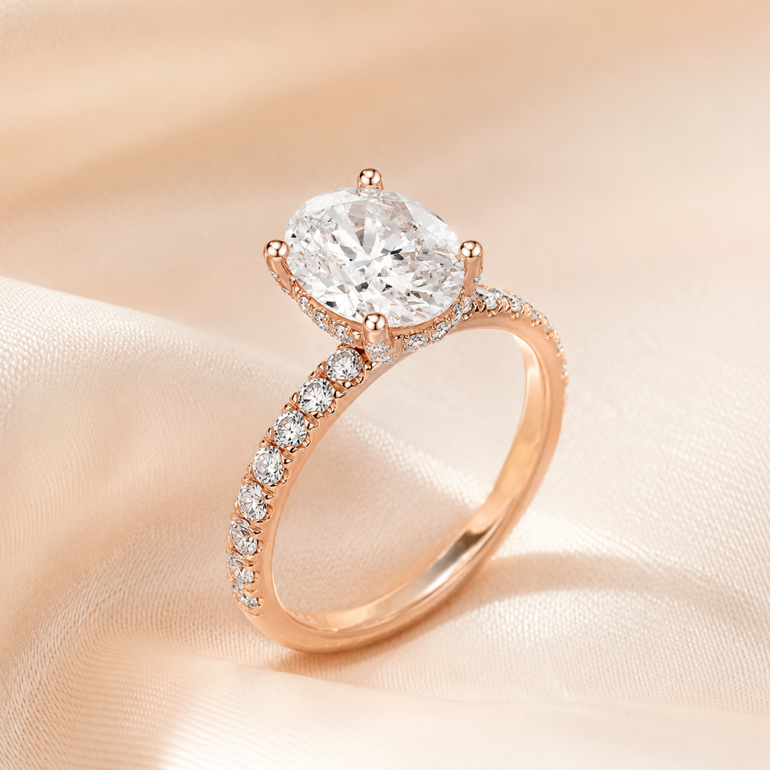 Rose gold solitaire engagement ring with a cushion-cut diamond center stone and pavé-set diamonds along the band, displayed on a soft beige satin fabric background.