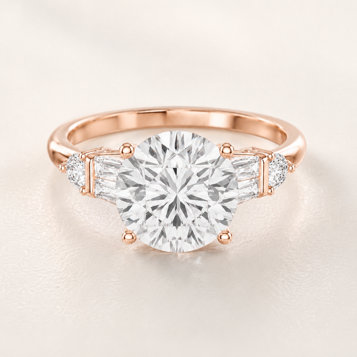 A rose gold engagement ring featuring a large round-cut center diamond flanked by baguette and round side diamonds, set against a clean, light beige background.