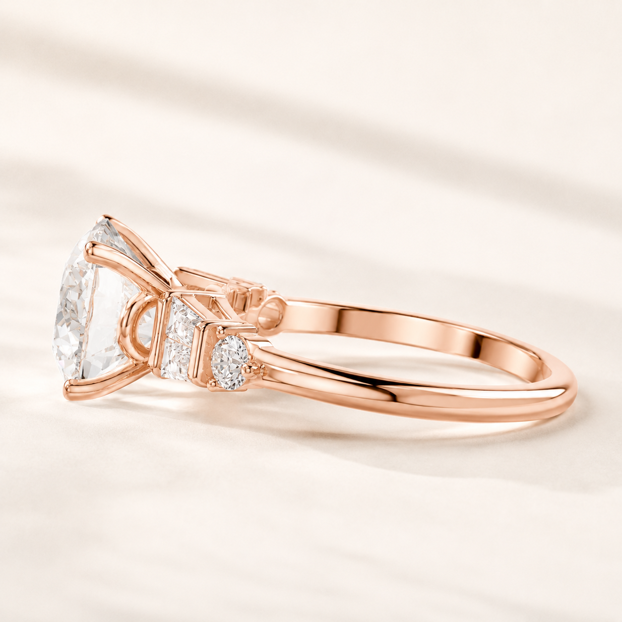 Rose gold engagement ring with a large oval-cut center stone and small pavé side stones, photographed on a soft cream background.