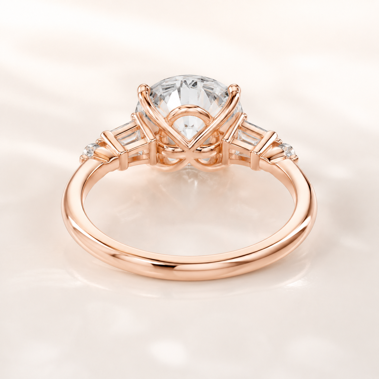 A rose gold engagement ring featuring a large round brilliant-cut center stone and baguette side stones, shown on a soft, light cream background.