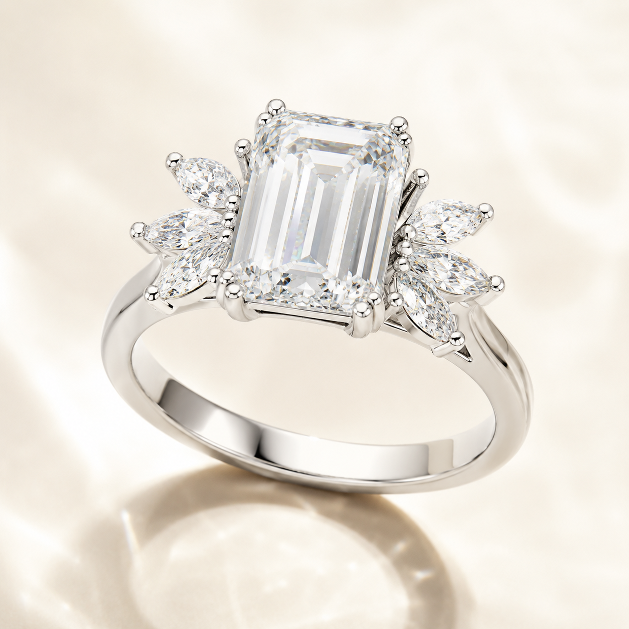 A silver engagement ring featuring a large emerald-cut center stone and marquise-cut side stones, displayed on a soft, light beige fabric background.