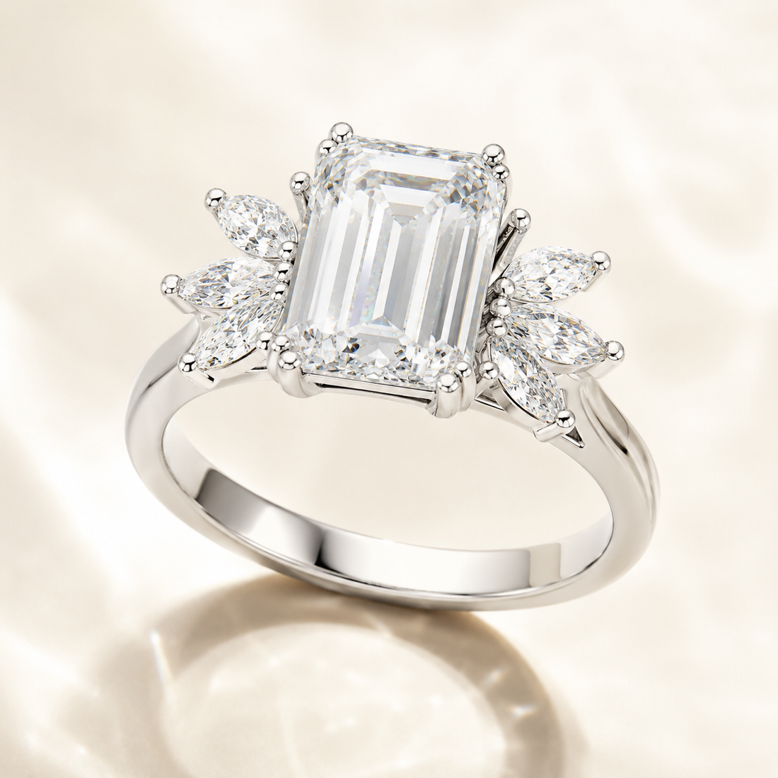 A silver engagement ring featuring a large emerald-cut center stone and marquise-cut side stones, displayed on a soft, light beige fabric background.