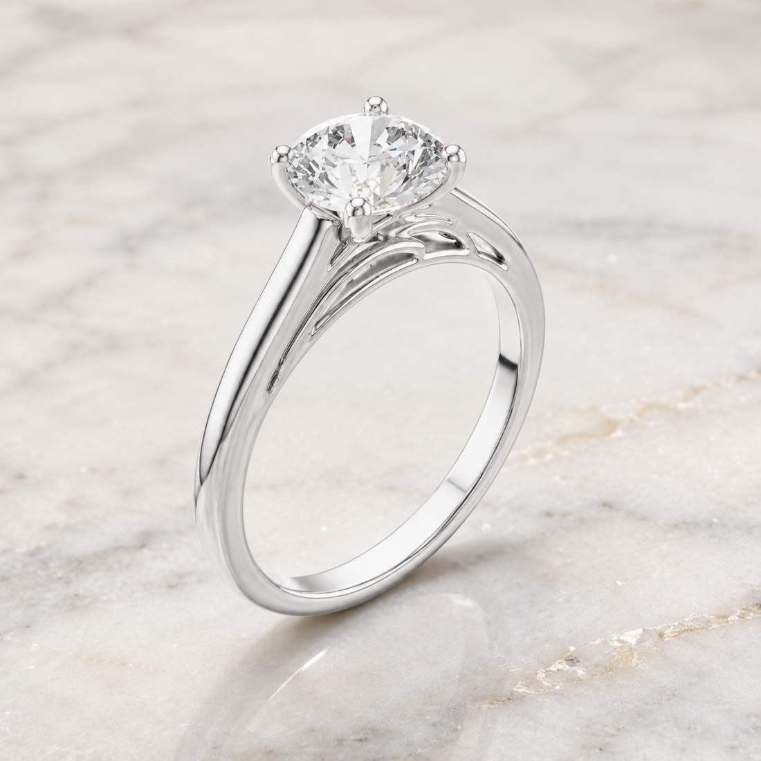 A silver solitaire engagement ring with a round brilliant-cut diamond, displayed on a light marble surface.