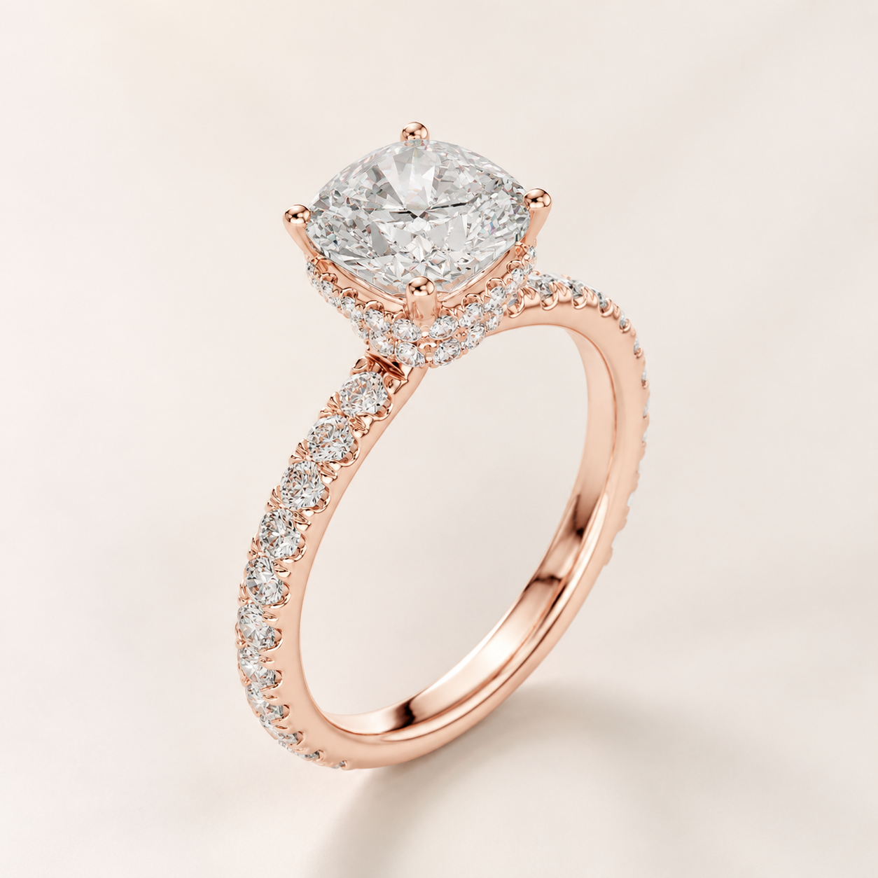 A rose gold engagement ring featuring a cushion-cut diamond center stone and a halo and pavé band, set against a soft beige background.