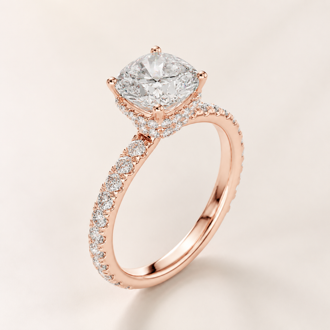 A rose gold engagement ring featuring a cushion-cut diamond center stone and a halo and pavé band, set against a soft beige background.