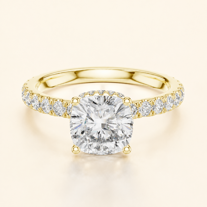 A yellow gold engagement ring featuring a large round brilliant-cut center diamond and a pavé-set diamond band, shown on a light cream background.