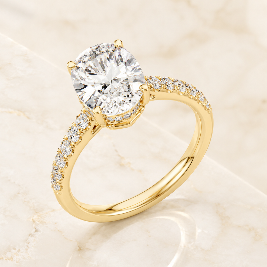 A yellow gold solitaire engagement ring with a round brilliant-cut center stone and a pavé-set diamond band, displayed on a light beige marble surface.