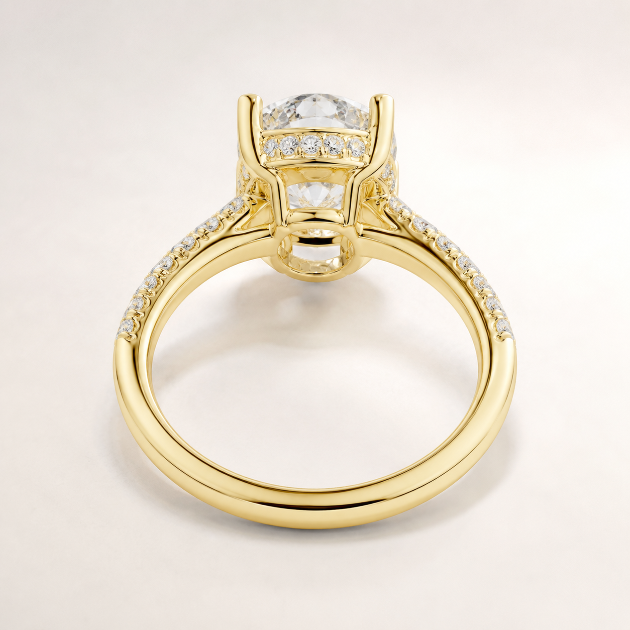 A yellow gold ring with a large round clear gemstone in a prong setting, accented by small pavé diamonds along the shoulders, shown on a light gray background.