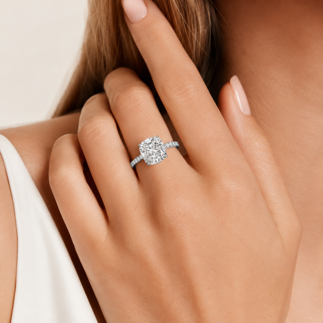 A close-up lifestyle shot of a woman's hand wearing a silver diamond engagement ring. The ring features a large round brilliant-cut center stone set in a silver band with small pavé accents.