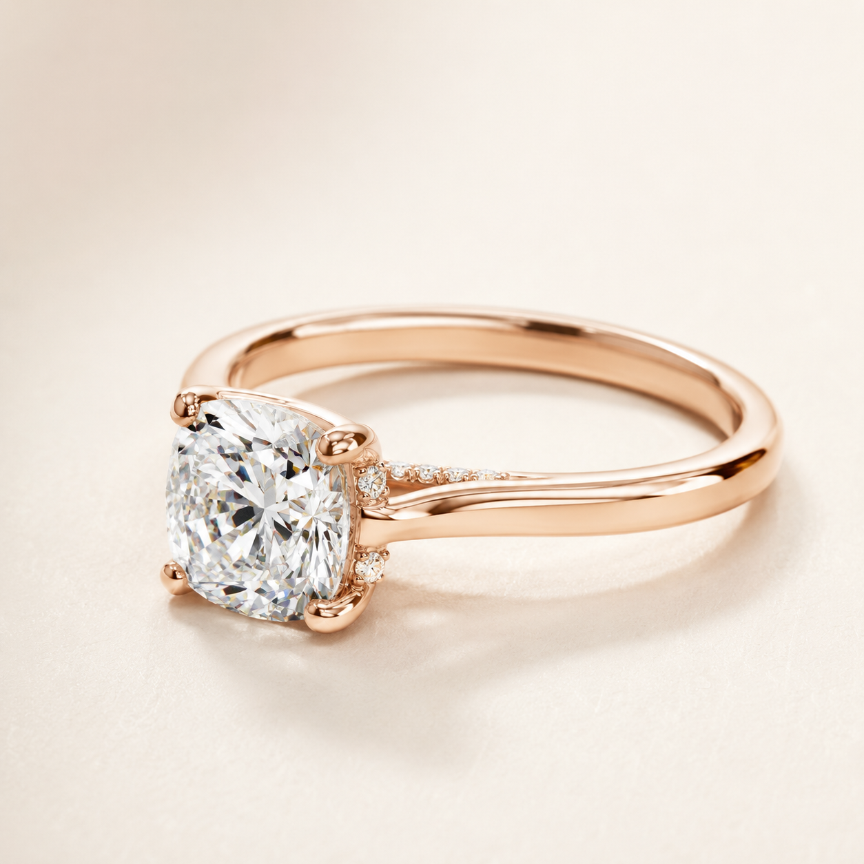 A rose gold engagement ring featuring a cushion-cut diamond solitaire and small accent diamonds on the band, set against a warm cream background.