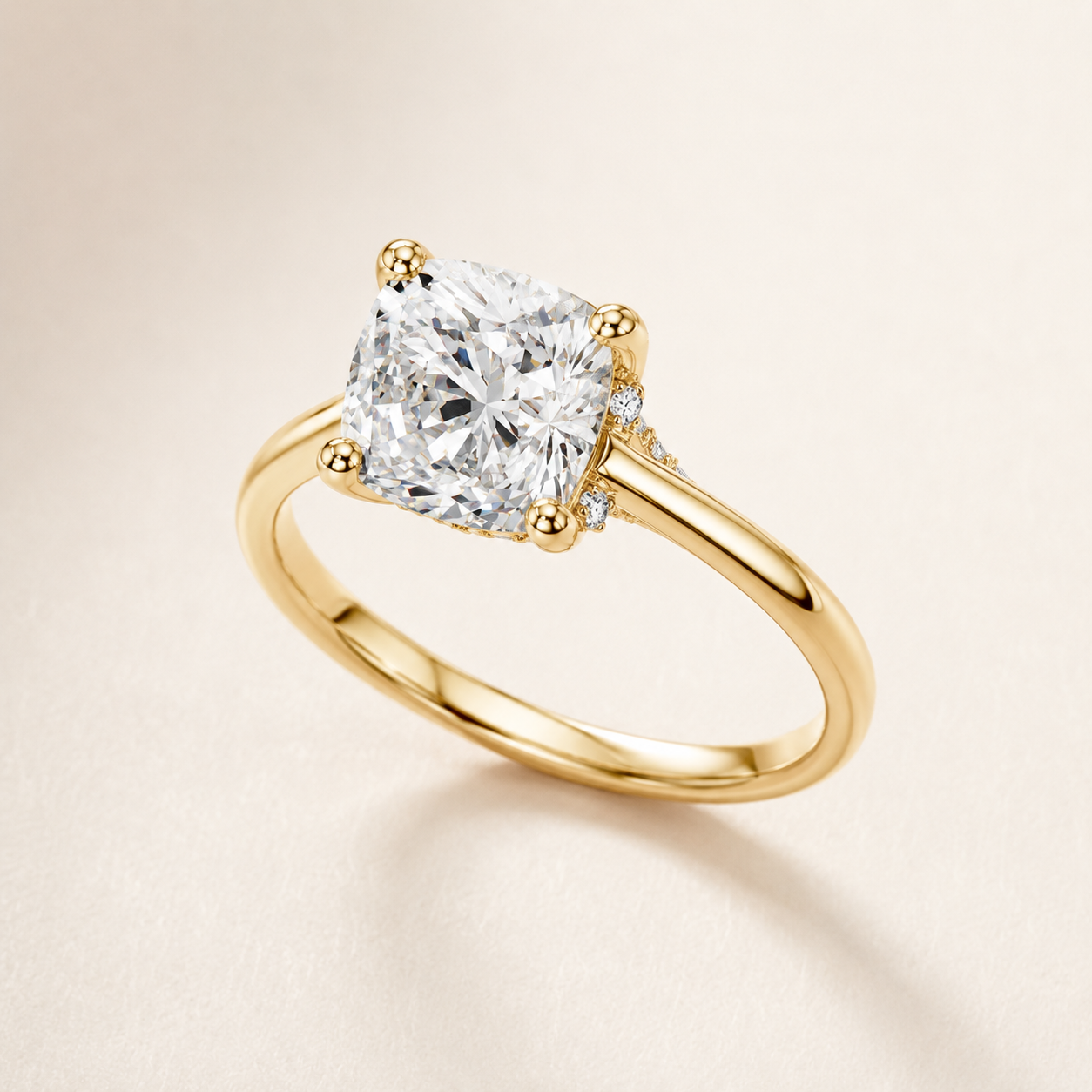 A yellow gold solitaire engagement ring featuring a large cushion-cut diamond center stone and a small accent diamond on the band, set against a soft beige background.