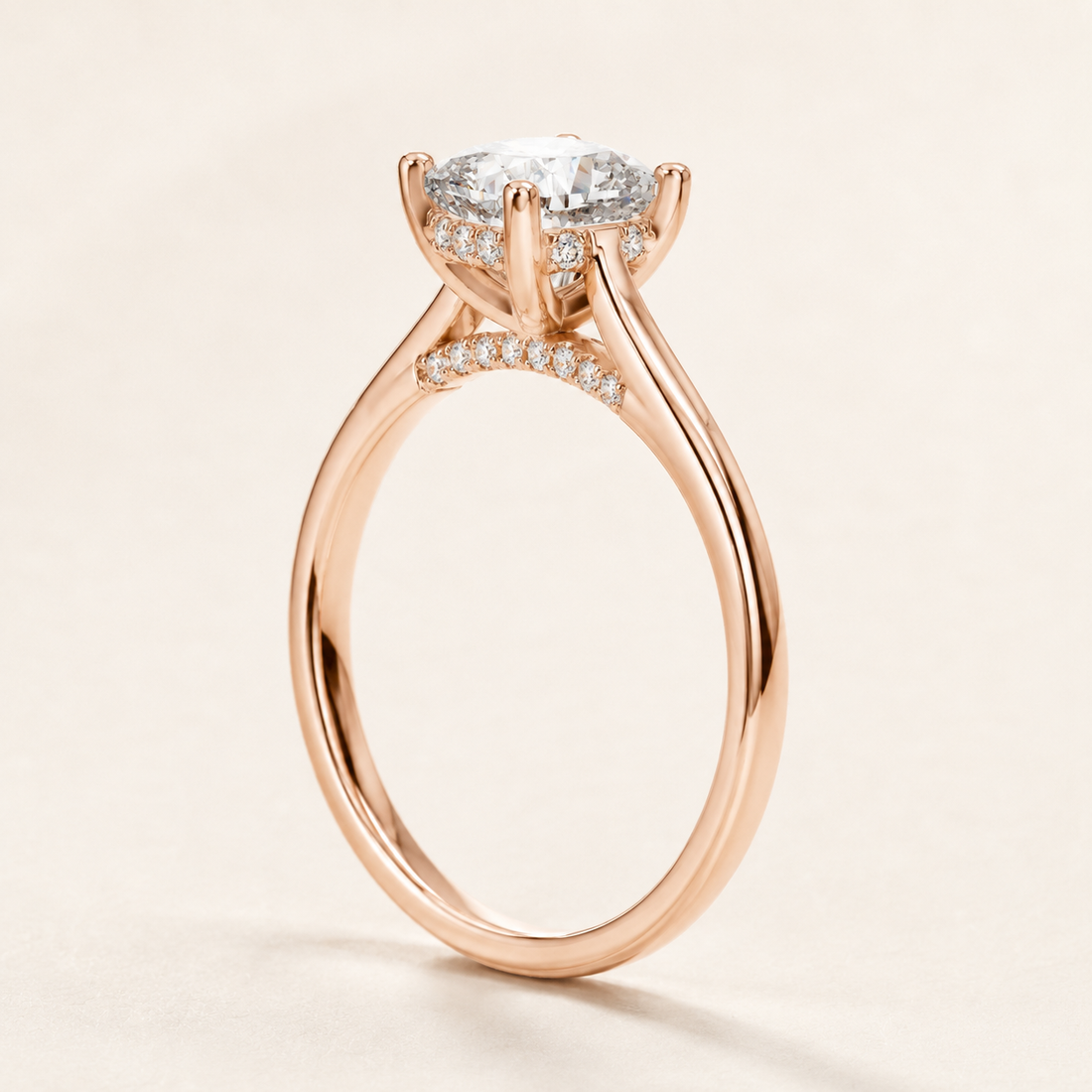 A rose gold engagement ring with a round-cut center stone and a halo of small pavé diamonds, shown on a clean, light beige background.