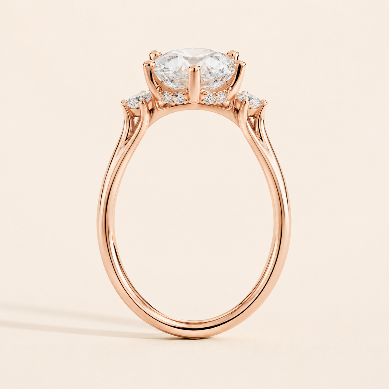 A rose gold engagement ring featuring a large oval-cut center stone and smaller accent stones along the shoulders, set against a solid light beige background.