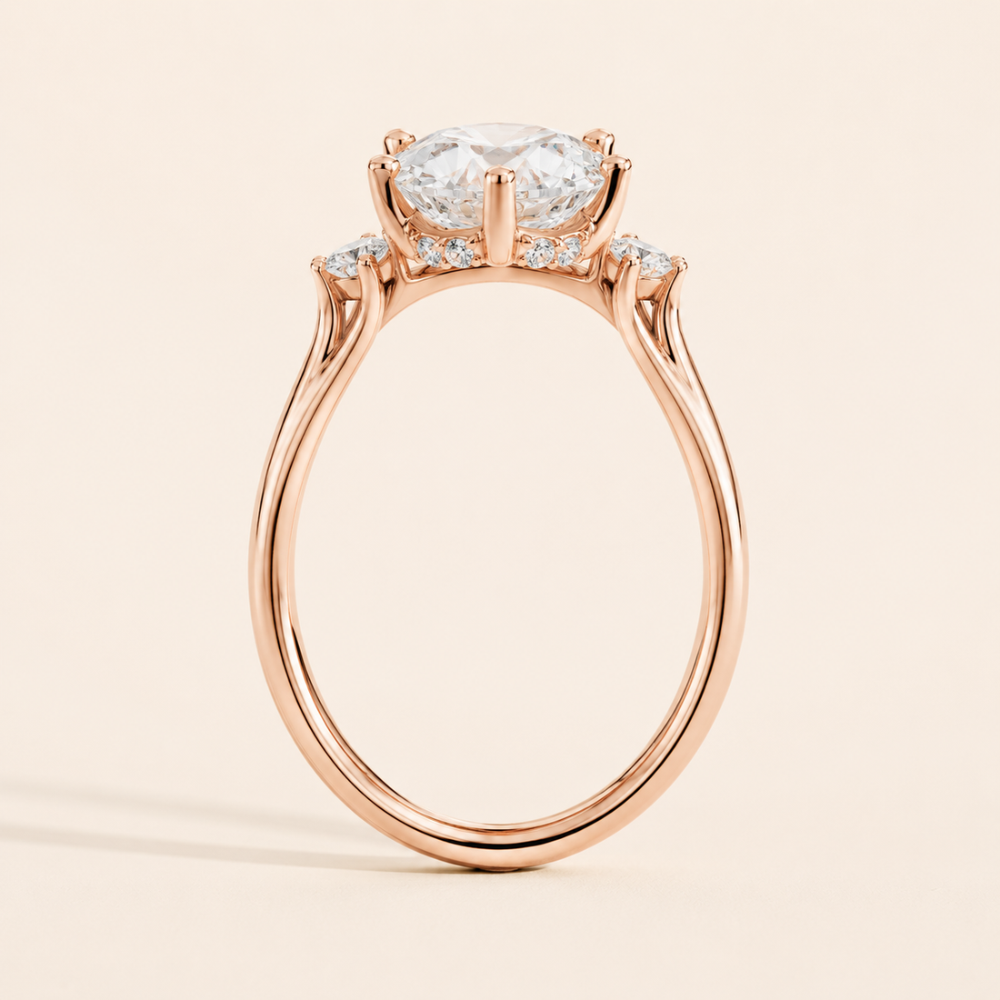 A rose gold engagement ring featuring a large oval-cut center stone and smaller accent stones along the shoulders, set against a solid light beige background.