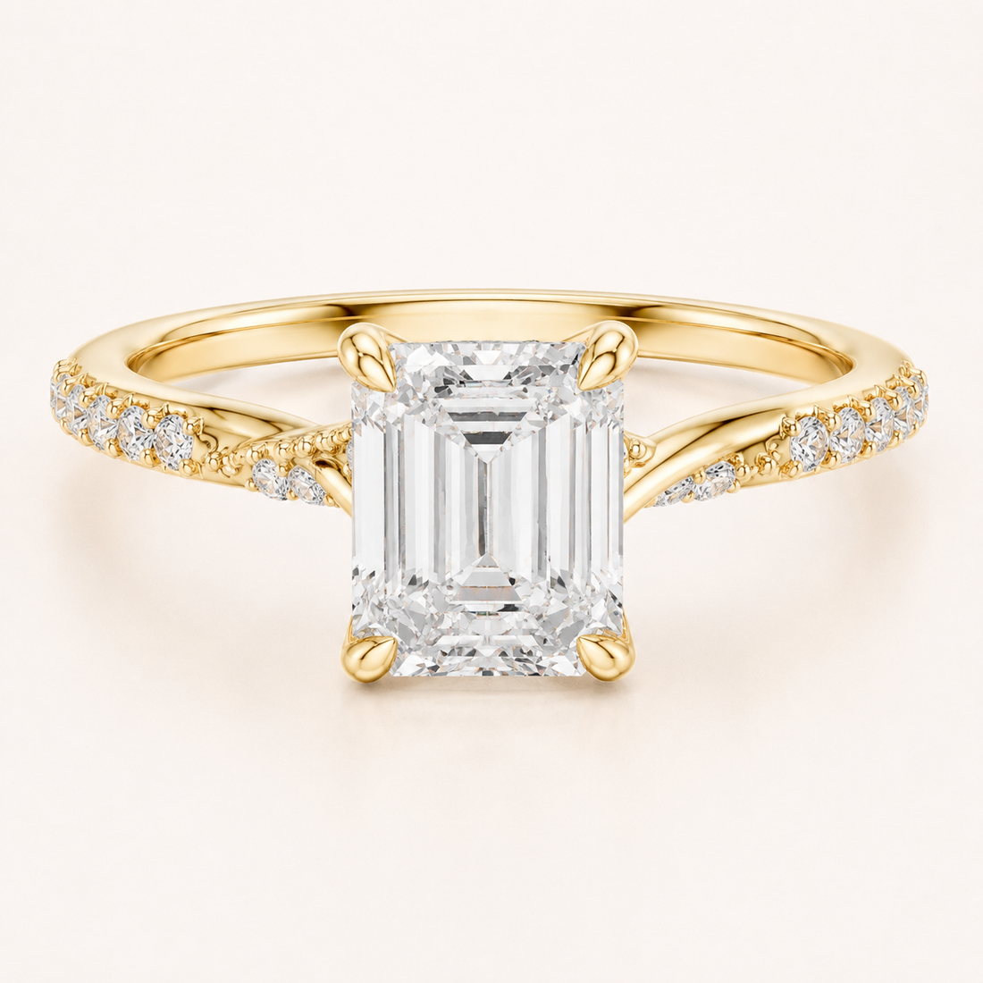 An emerald-cut diamond engagement ring in yellow gold, featuring a large central diamond and smaller diamonds set along the shoulders of a polished band, shown on a light cream background.
