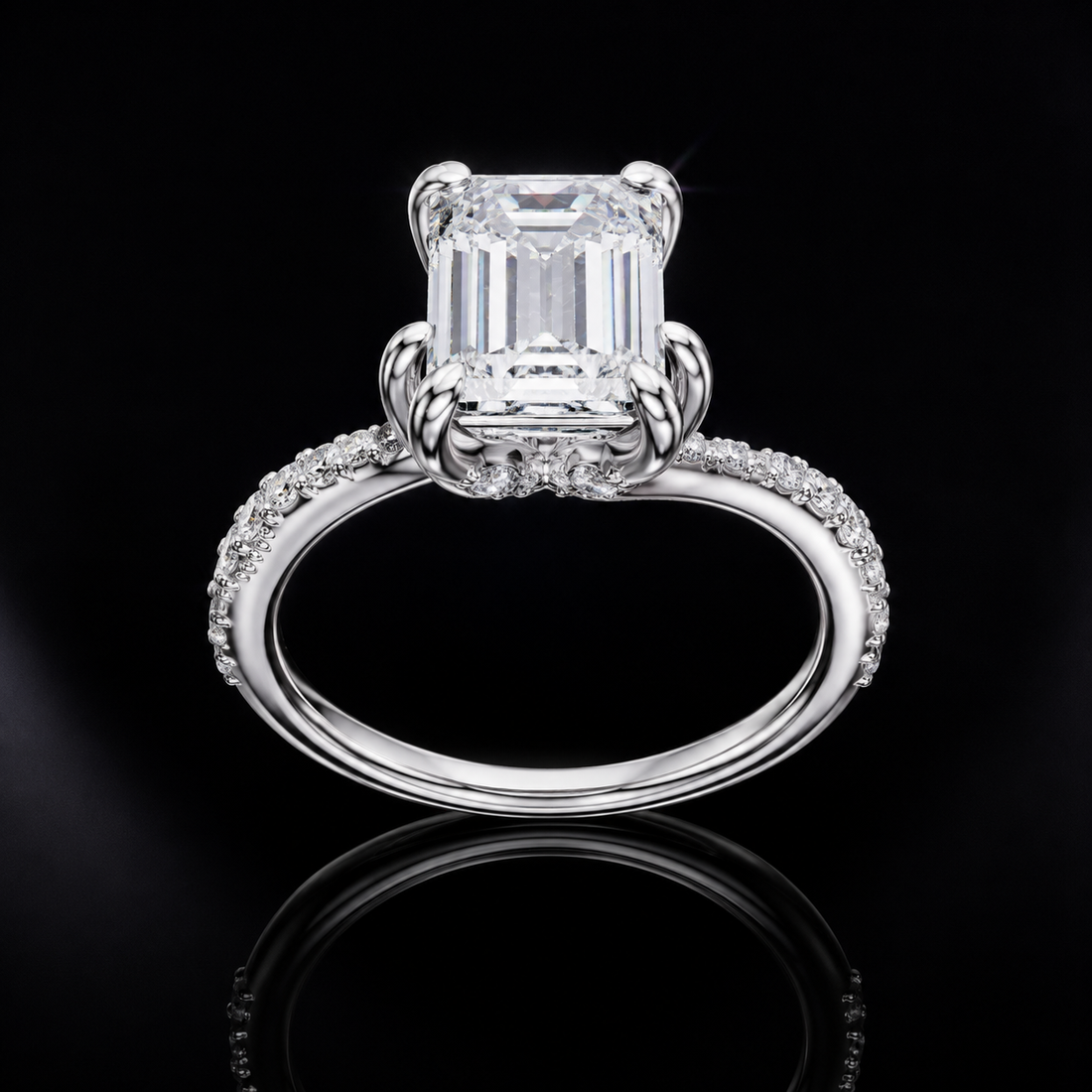 An emerald-cut diamond ring in a polished silver-toned setting with a pavé band, displayed on a reflective black background.